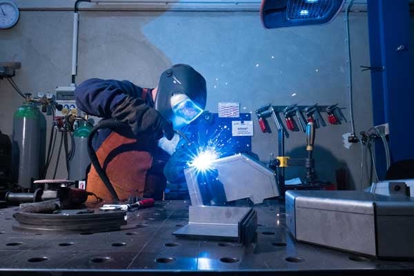 A person in protective workwear carries out welding work in BeeWaTec's in-house production.