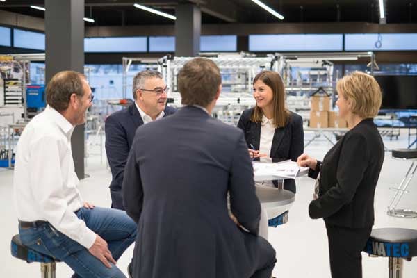 Die Geschäftsleitung und BeeWaTec Mitarbeitende unterhalten sich im Ausstellungsraum von BeeWaTec.