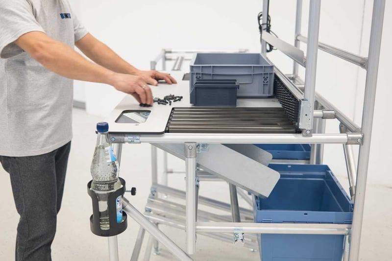 Employee assembles at a BeeWaTec industrial workstation made of round aluminum profile tubes