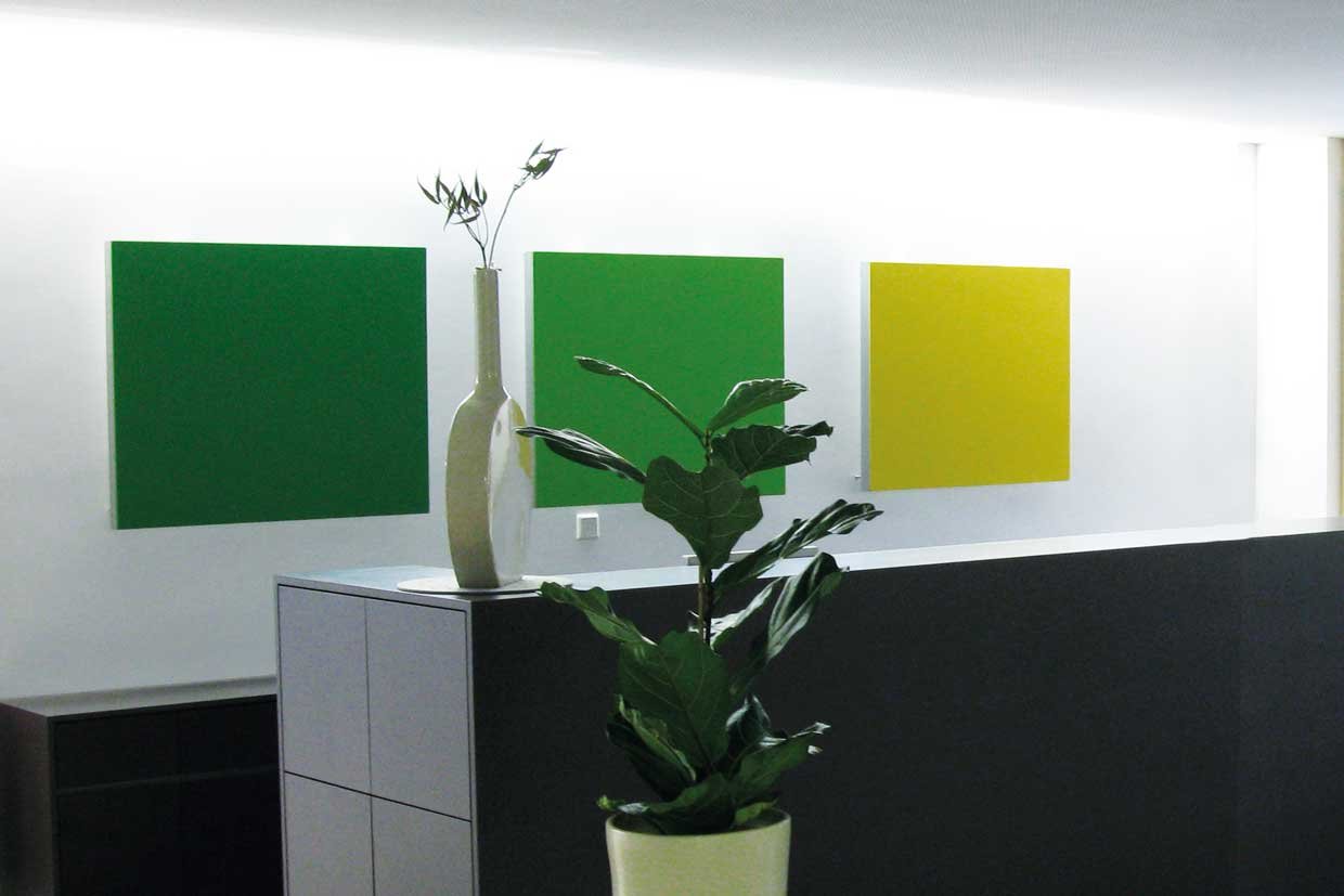 Three square wall panels hang on the wall behind a reception counter in a visually appealing way